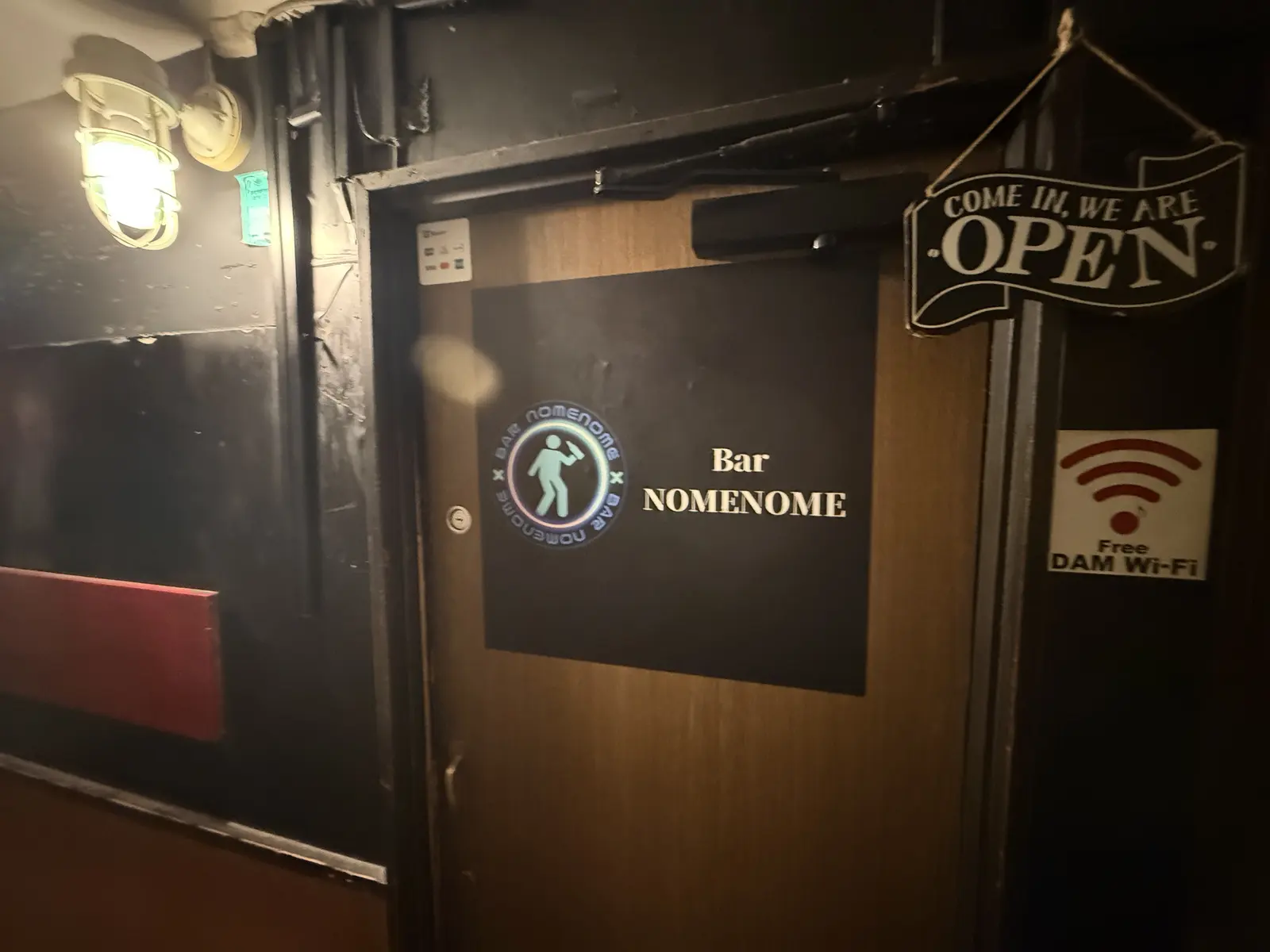 中銀新橋ビル地下1階のBAR NOMENOMEの扉。ロゴの看板と「OPEN」の札